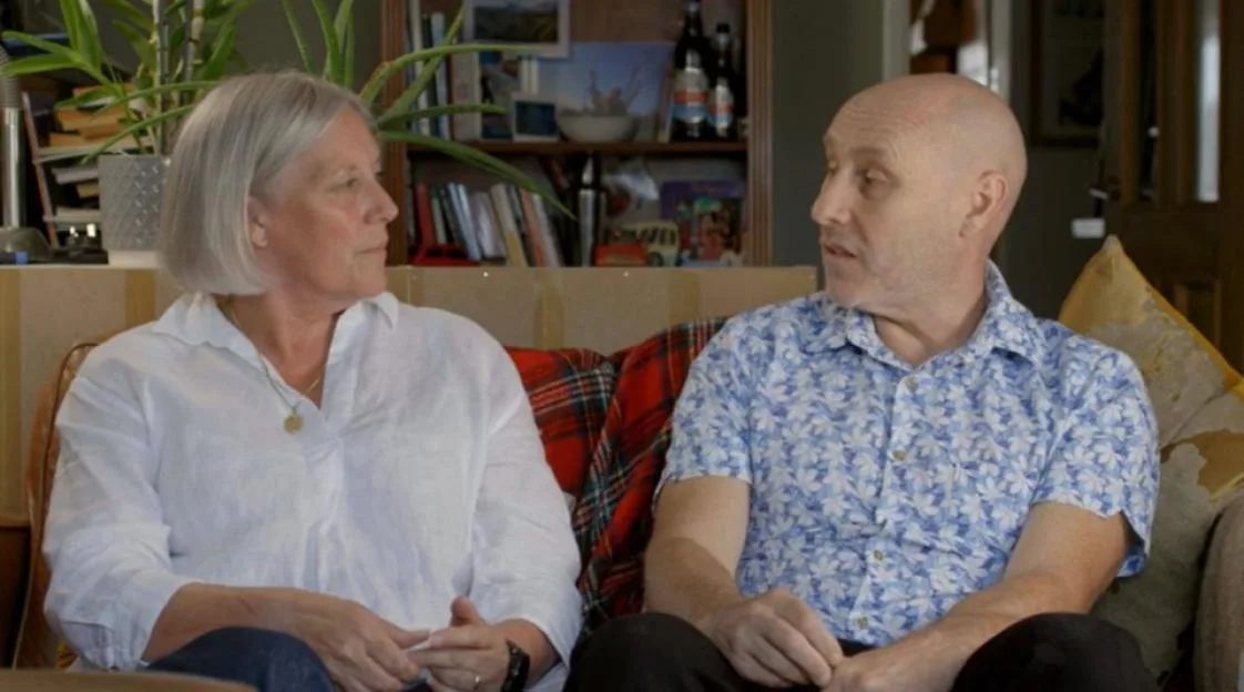 A man and woman sitting on a couch.