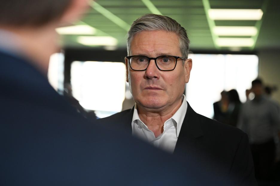 Keir Starmer, with gray hair and glasses, speaks to the media.