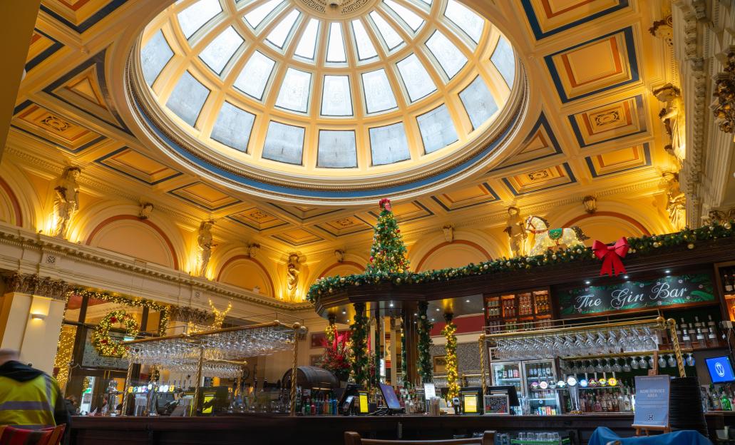The ornate interior of The Counting House pub and restaurant, featuring a large dome skylight, Christmas decorations, and a bar counter.