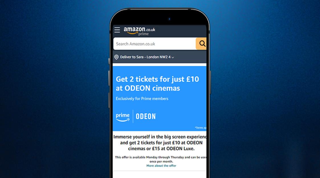 A smartphone displaying an Amazon.co.uk Prime offer for 2 cinema tickets at ODEON for £10.