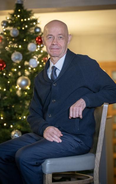 A man sitting in front of a Christmas tree.
