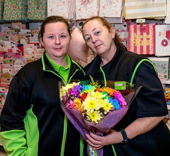 Katie and her mother Cheryl holding a colorful bouquet of flowers in an Asda store display for Mother's Day.