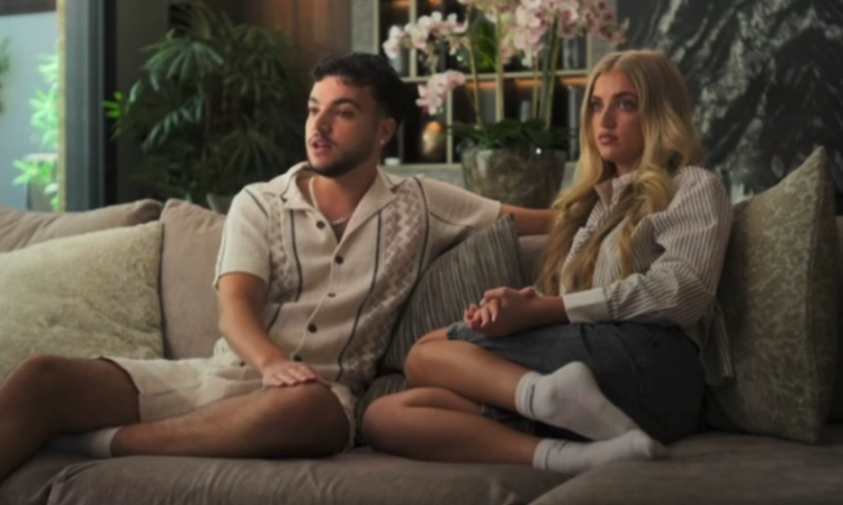 A young man and woman sitting on a couch, looking to the left.