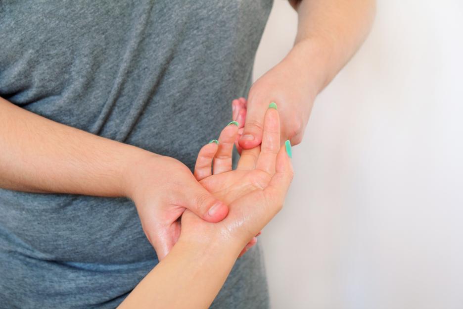 A person giving a hand massage to another person with green painted fingernails.