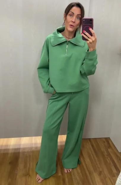 A woman models a green sweatshirt and matching wide-leg pants.