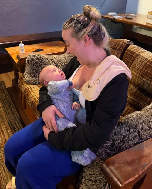 A young woman holding her baby and looking at him lovingly.