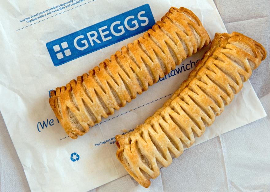 Two Greggs Vegan Sausage Rolls on paper bag with paper napkins behind.