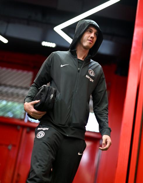 Cole Palmer, wearing a Chelsea training kit, walks through a stadium tunnel.