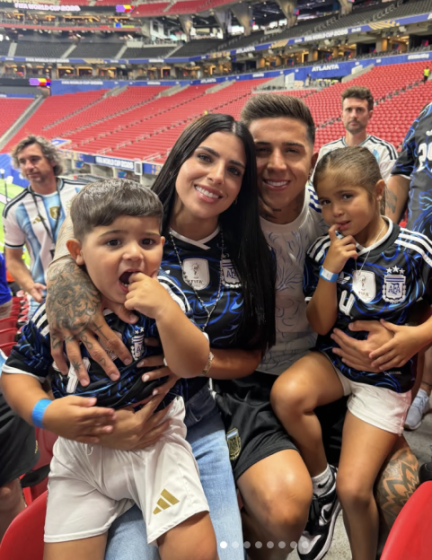 A family wearing Argentina soccer jerseys watches a game in a stadium.