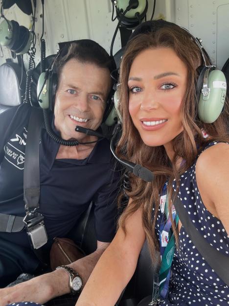 Lorna Lux and a man smiling while wearing headphones in a helicopter.