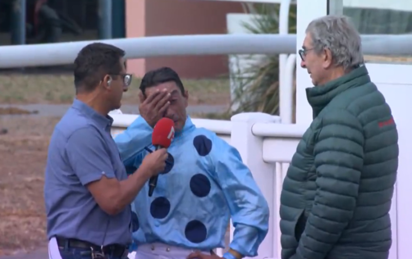 Interview with a jockey covering his face, a reporter, and an observer.