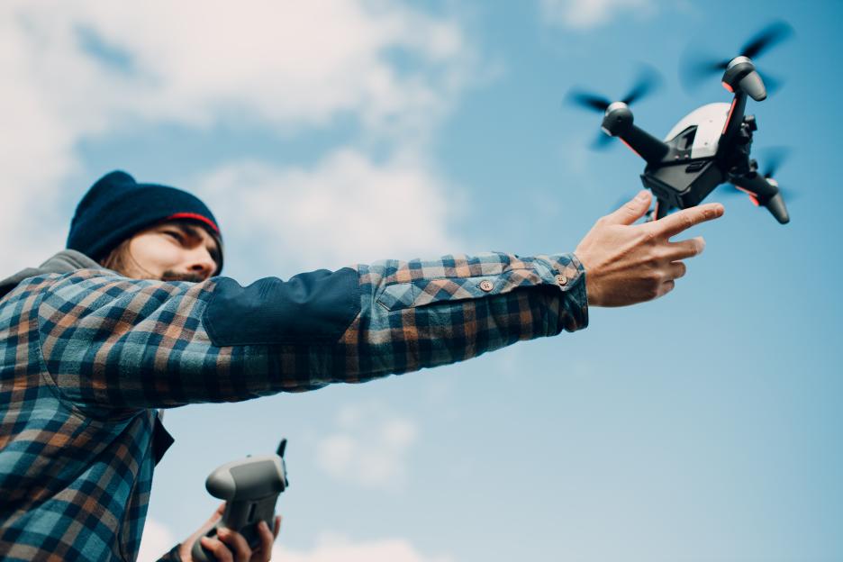 Man launching a quadcopter drone into the sky.