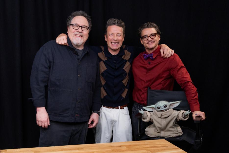 Jamie Oliver, Jon Favreau, and Pedro Pascal posing with a Grogu plush toy.