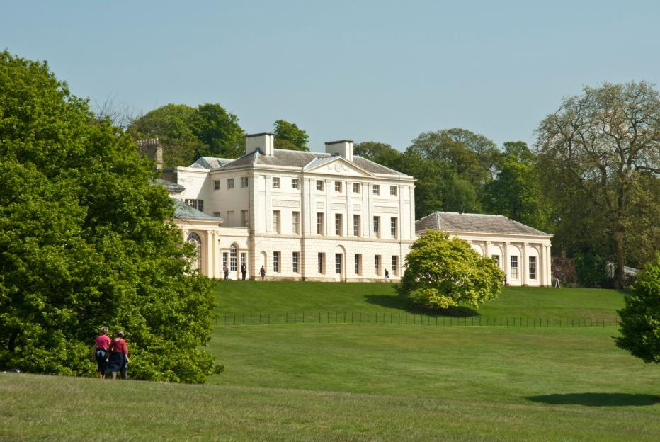 Kenwood House, London, surrounded by mature trees and parkland on a sunny day.
