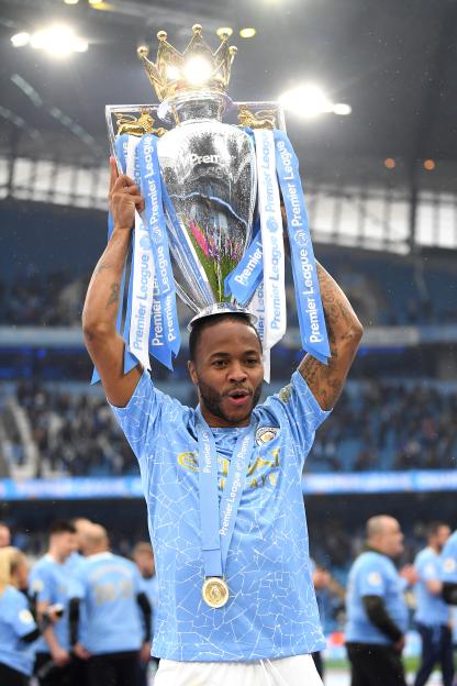 Manchester City player Raheem Sterling holding up the Premier League trophy.