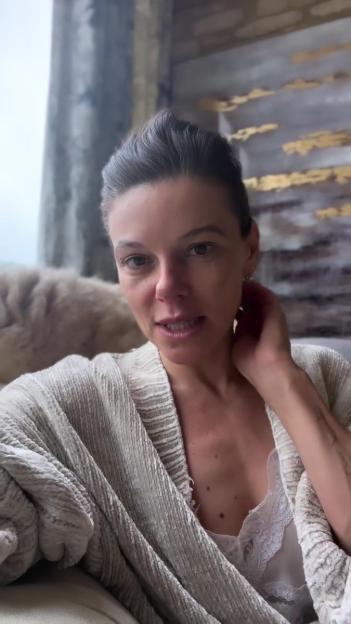 Faye Brooks in a white cardigan and white lace top looking at the camera.