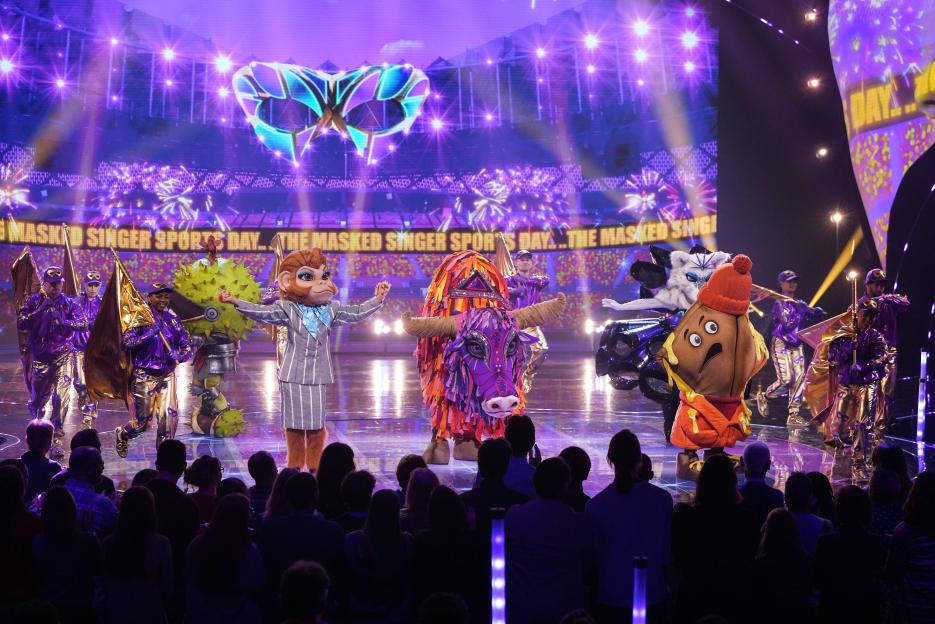 Five costumed characters, Conkers, Monkey Business, Yak, Toastie, and Arctic Fox, on stage for "The Masked Singer Sports Day."