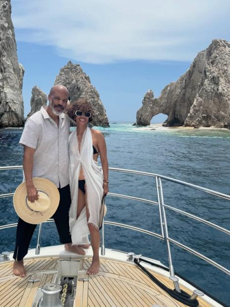 A man and woman standing on a boat with rock formations in the background.