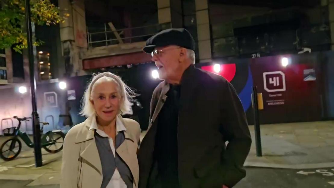 Helen Mirren walking with her husband Taylor Hackford on a street at night.