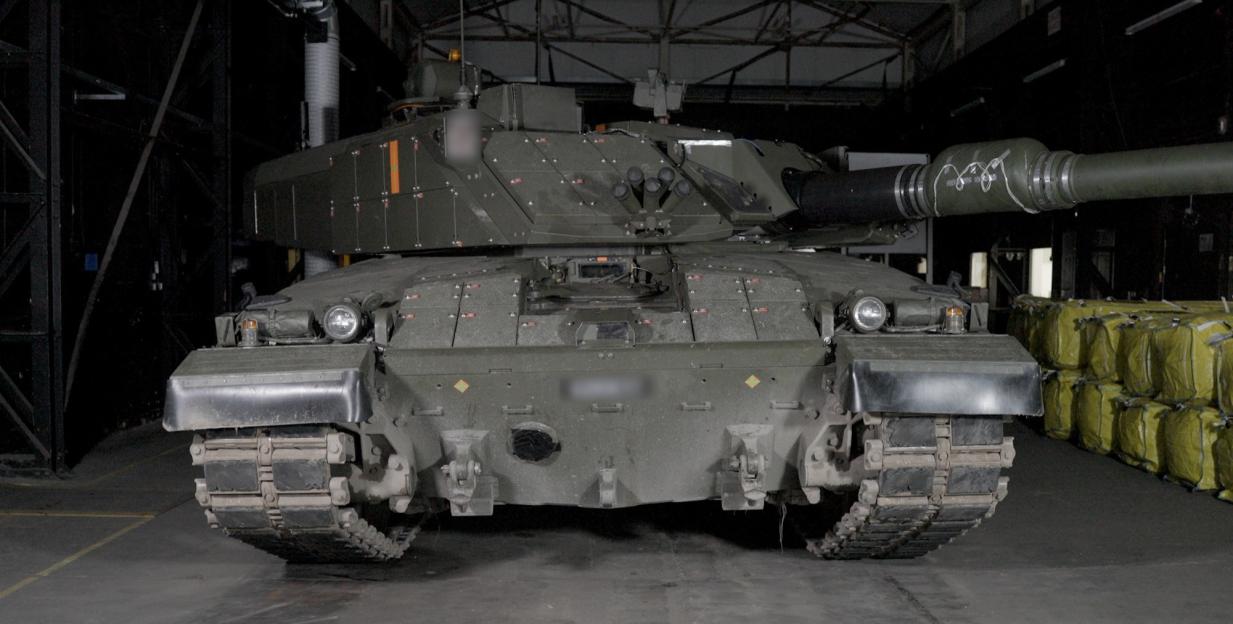 Front view of a Challenger 2 tank with its turret facing forward and its gun barrel extending to the right.
