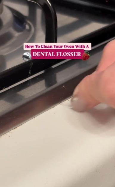 A person uses dental floss to clean the crevice of an oven or stovetop.