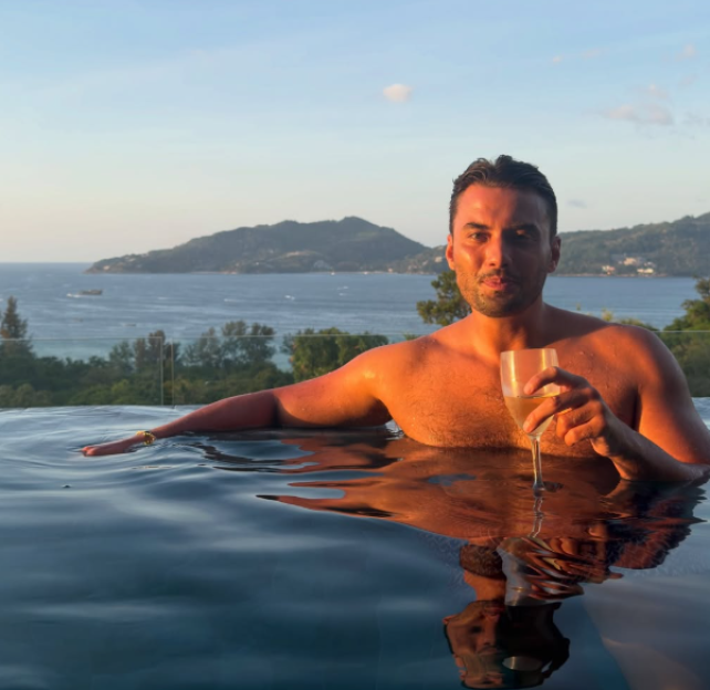 Man in infinity pool with a glass of champagne.