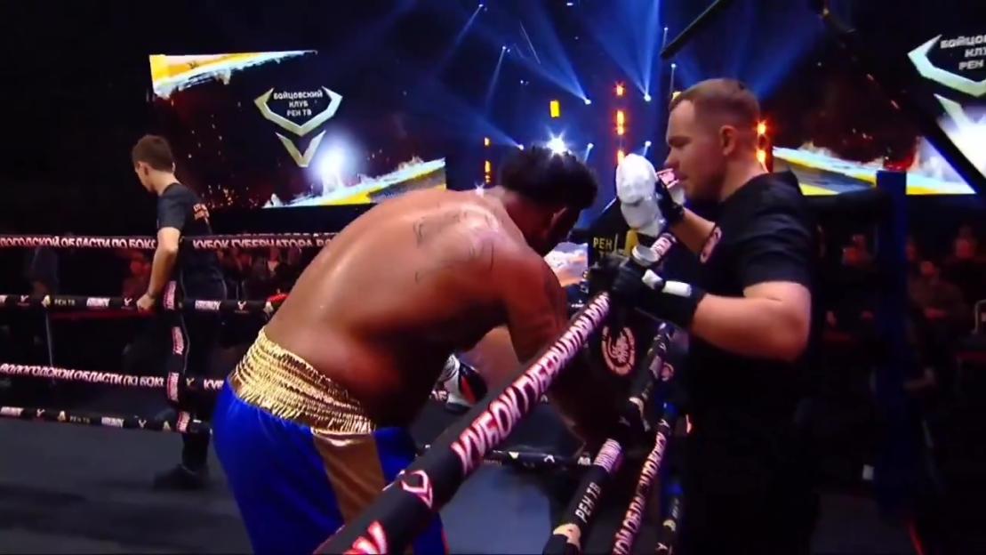 An NFL star-turned-boxer collapses into the corner of a boxing ring.
