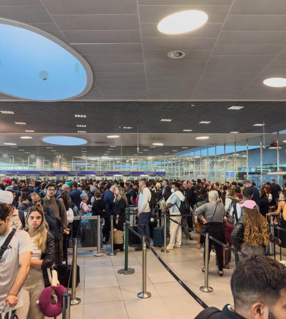 Long lines of passengers waiting for immigration border control processing at Lisbon Humberto Delgado Airport.