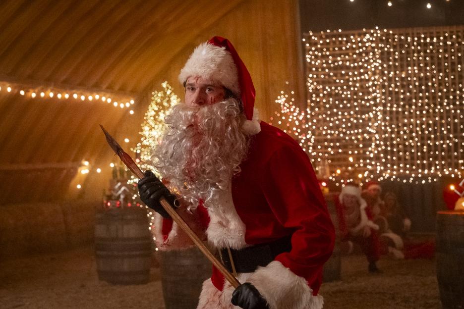 Rohan Campbell as Billy Chapman, dressed as a bloody Santa Claus, holding a bloodied spear.
