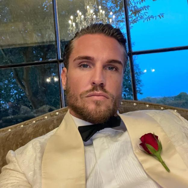 Thomas Zanetti in a cream tuxedo with a red rose.