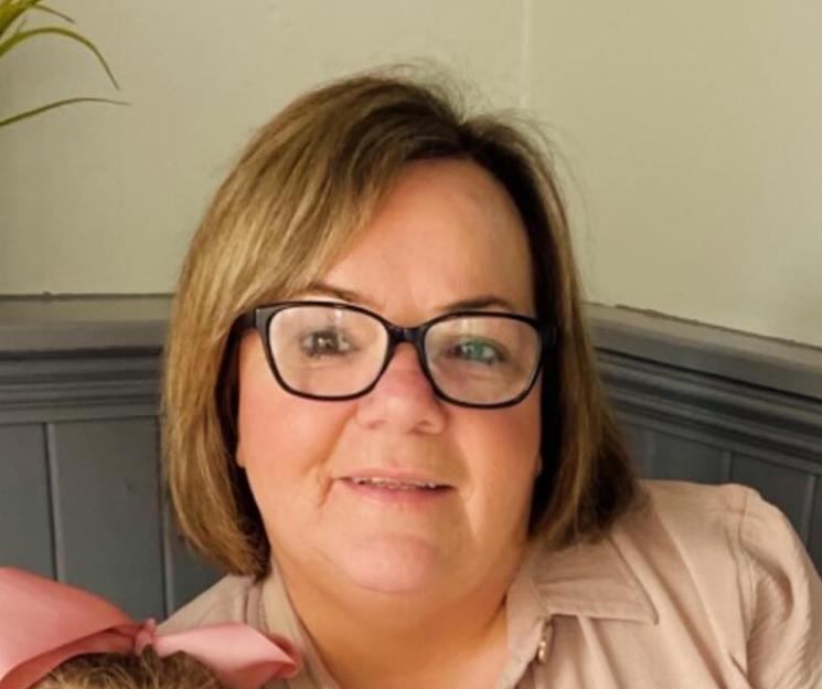 a woman wearing glasses and a pink shirt is smiling