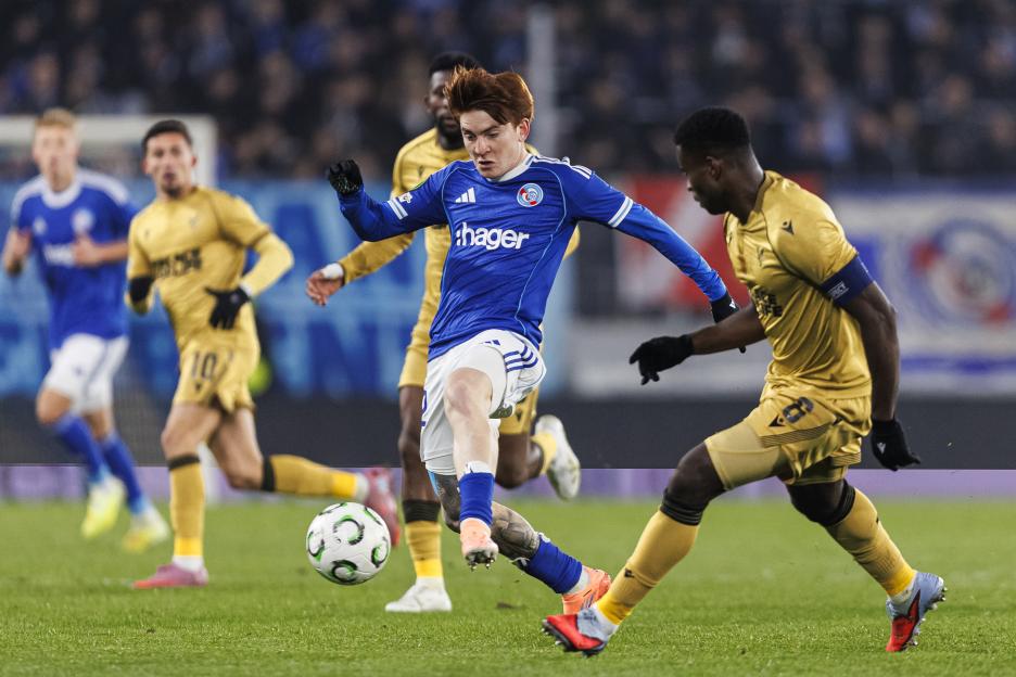 Racing Club de Strasbourg Alsace player dribbling the ball past Crystal Palace FC players during a UEFA Conference League match.