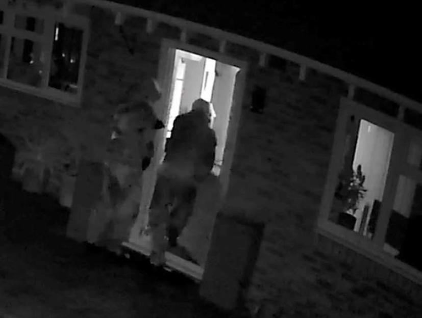 Surveillance footage of two masked burglars entering a home at night.