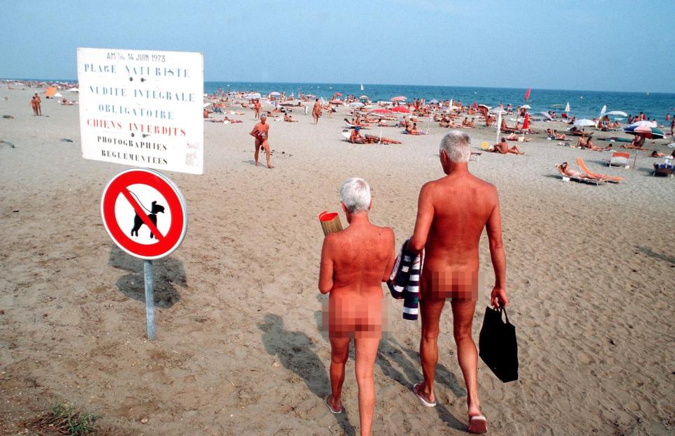 Couple walking on a naturist beach.