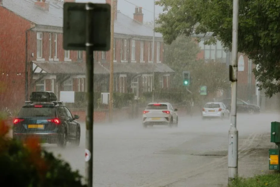 Cars driving through torrential rain on a street in North Manchester.
