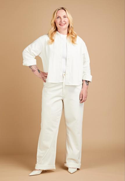 Anniki Sommerville trying on jeans, wearing a white shirt and wide-leg white jeans with white heels.