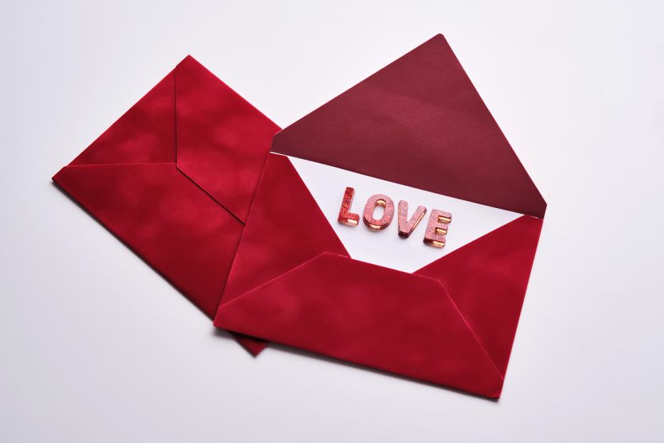 Two red envelopes on a white background, one open revealing the word "LOVE" in glittery letters.