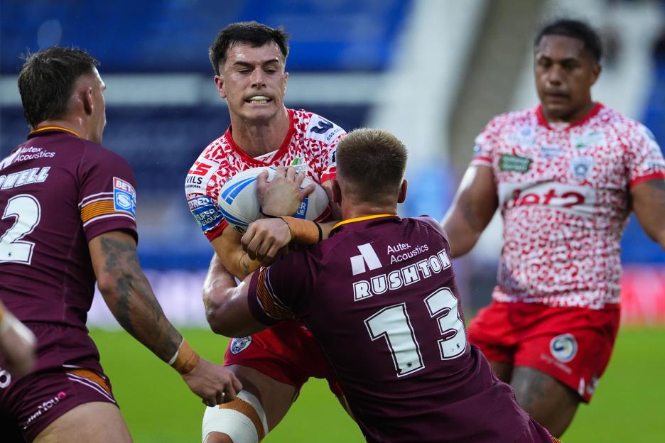Huddersfield Giants player Adam Rushton tackles Leigh Leopards player Ben Reynolds who is carrying the ball.