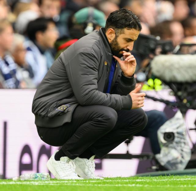 Manchester United manager Ruben Amorim squats on the sidelines of the Tottenham Hotspur Stadium.