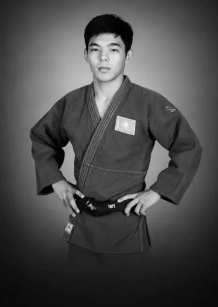 Black and white photo of Serzhan Ayapbergen, 20, in a judo uniform.