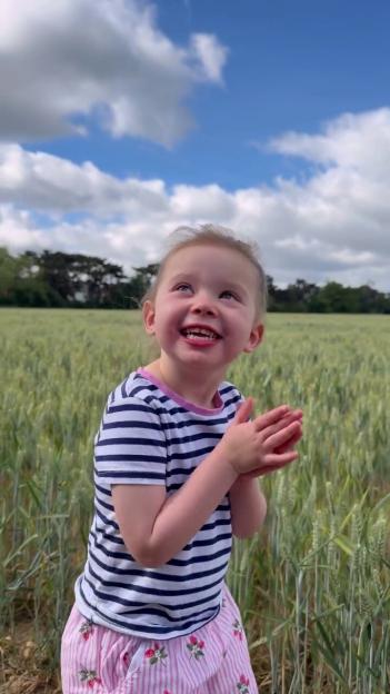 Nora, the daughter of Love Island's Camilla Thurlow, smiling and looking up in a field.
