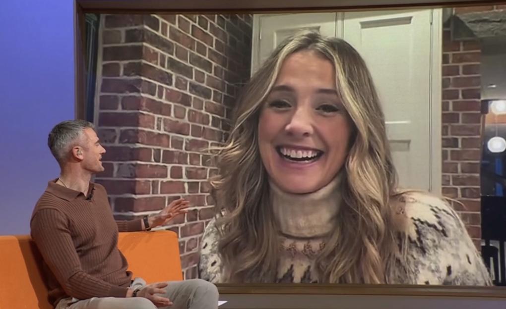 A TV presenter appearing on a video call laughs as her co-host gestures to a part of the screen where her husband was seen crawling in the background.