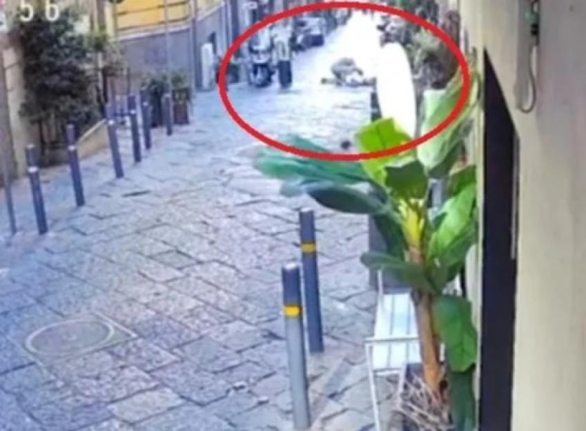 CCTV footage of a person lying on the ground in a narrow street, circled in red.