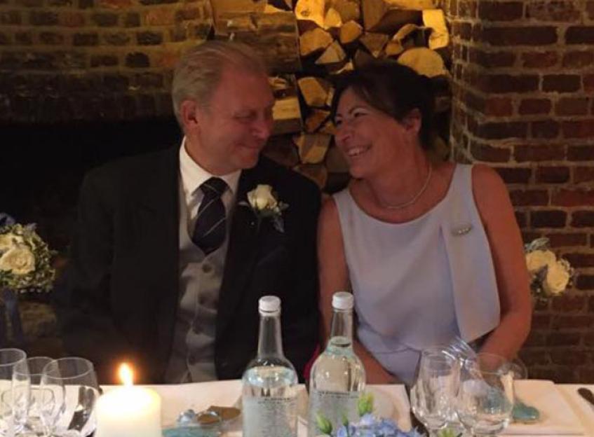 Philip and Sandra Thomas looking at each other across a table set for dinner.