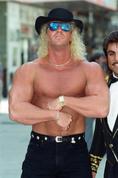 American wrestler Van Hammer flexing his biceps while wearing a cowboy hat and reflective sunglasses.