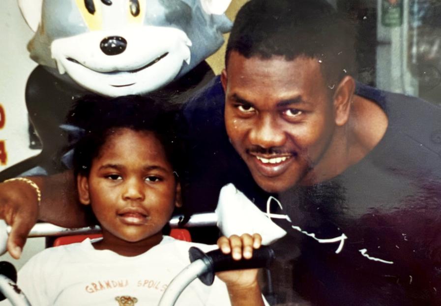 A young girl and her father posing for a picture in front of a Tom and Jerry statue.