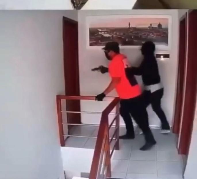 Robbers with a gun in a hallway.