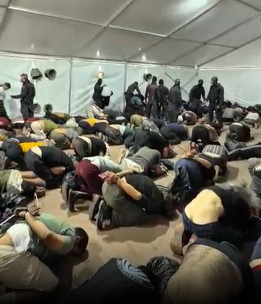 Flotilla activists bound and forced to lie on the floor while security personnel stand over them.