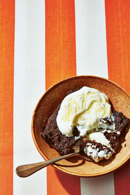 Chocolate brownie with ice cream on an orange and white striped tablecloth.