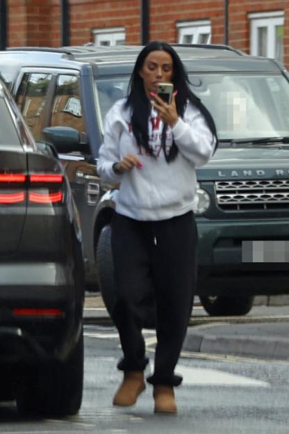 Katie Price walking near her home, holding a phone.